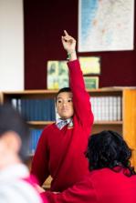 Student raises his hand during classroom discussion.
